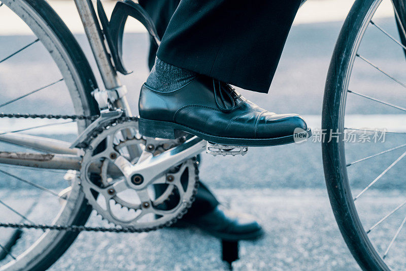 近距离拍摄的一个中年男人的商业鞋而骑自行车