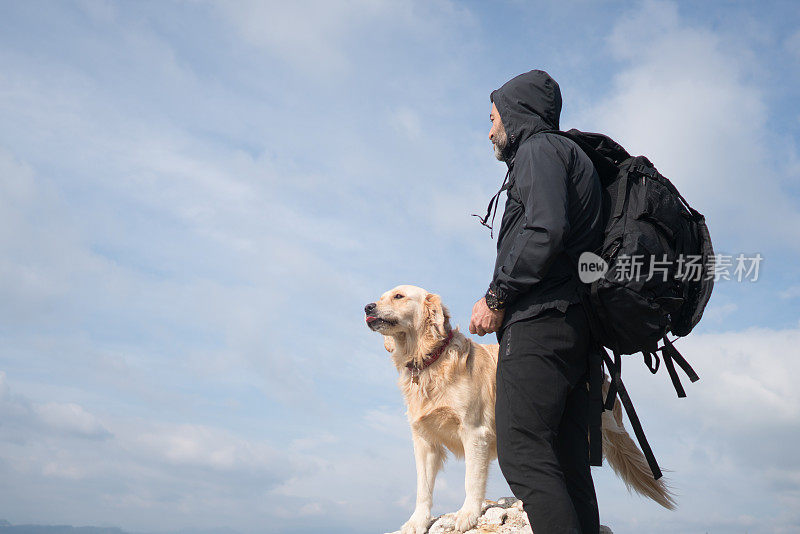 一个徒步旅行者和他的狗站在山顶上。