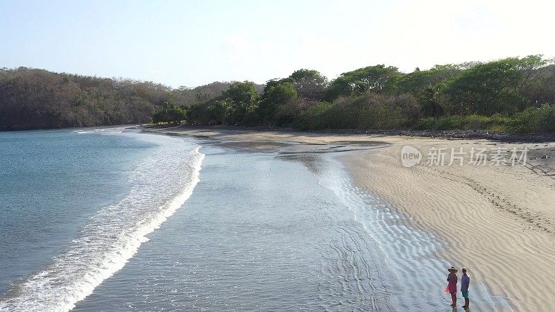 鸟瞰图的成熟夫妇走下海滩在日出