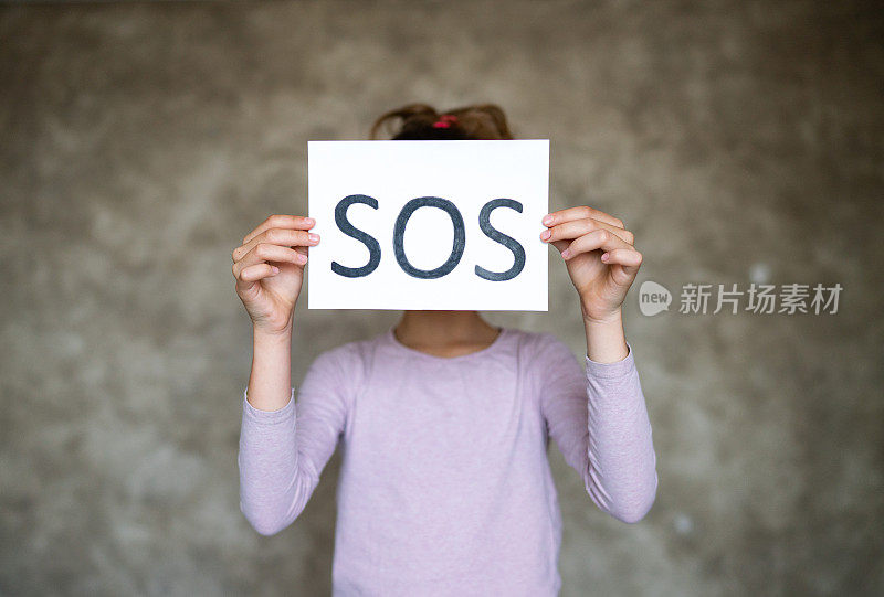 女孩举着“SOS”的牌子