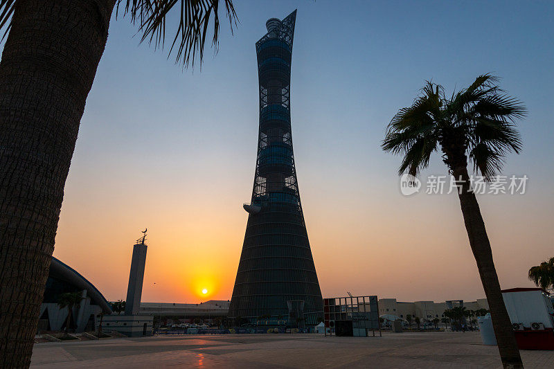 多哈体育城市综合体的火炬塔在日落时，旁边的Aspire清真寺在晴朗的天空下