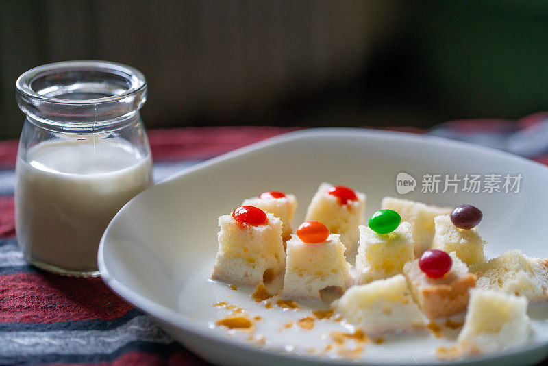 早餐有一杯牛奶和麦片，上面装饰着五颜六色的软糖。孩子们的早餐小吃