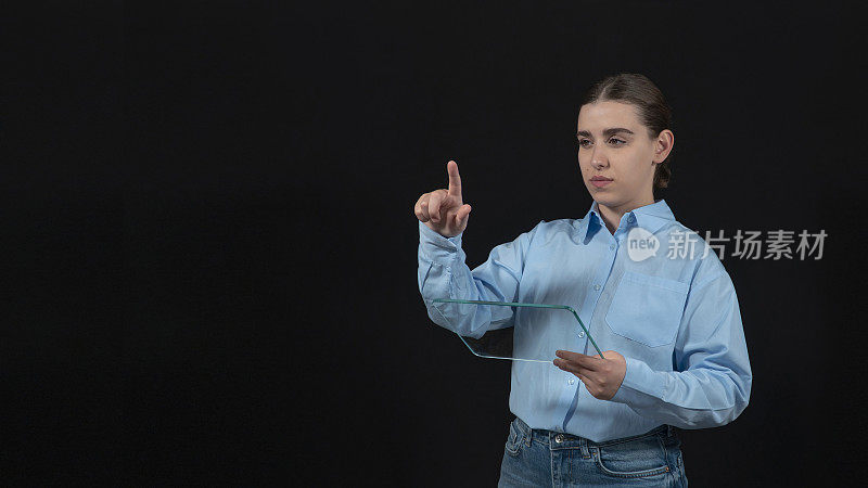 年轻女子触摸传感器表面。年轻女子拿着一块透明的玻璃。技术的概念。