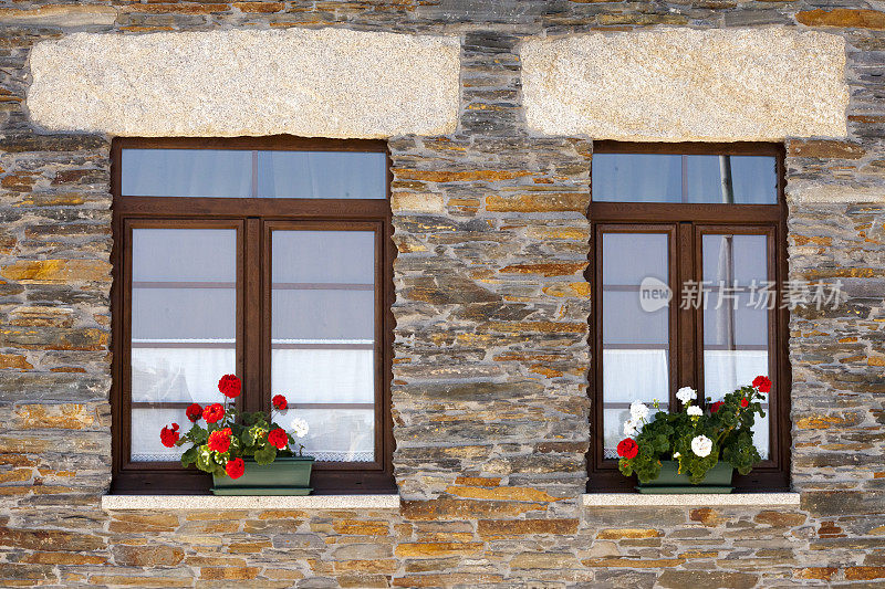 修复的石头房子的细节，两扇窗户和花盆。