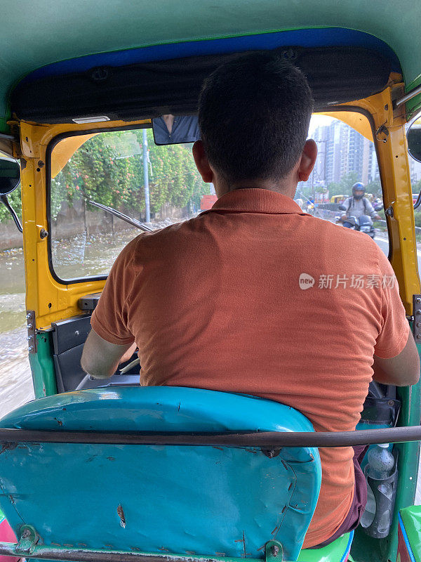 绿色和黄色机动三轮车的嘟嘟司机的乘客视角特写图像，后视图，聚焦前景