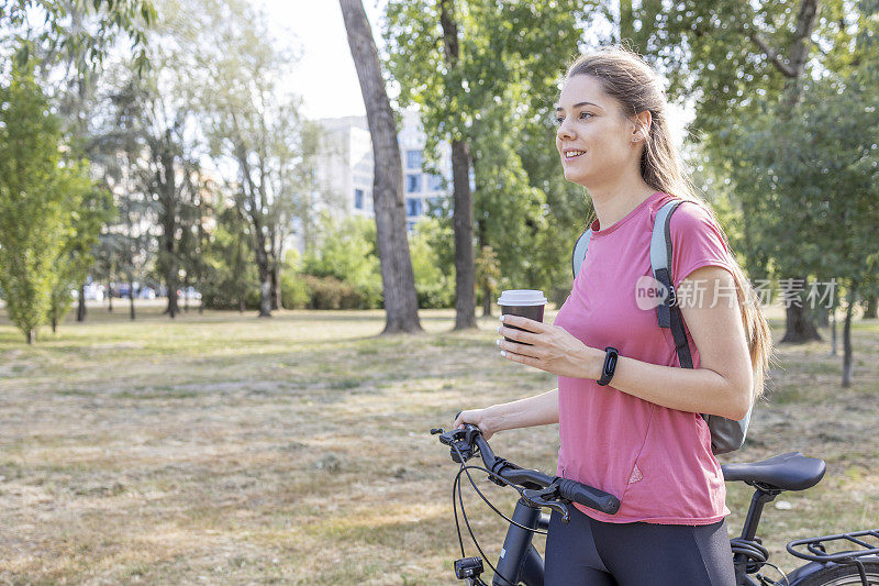 年轻女子推着自行车喝着咖啡