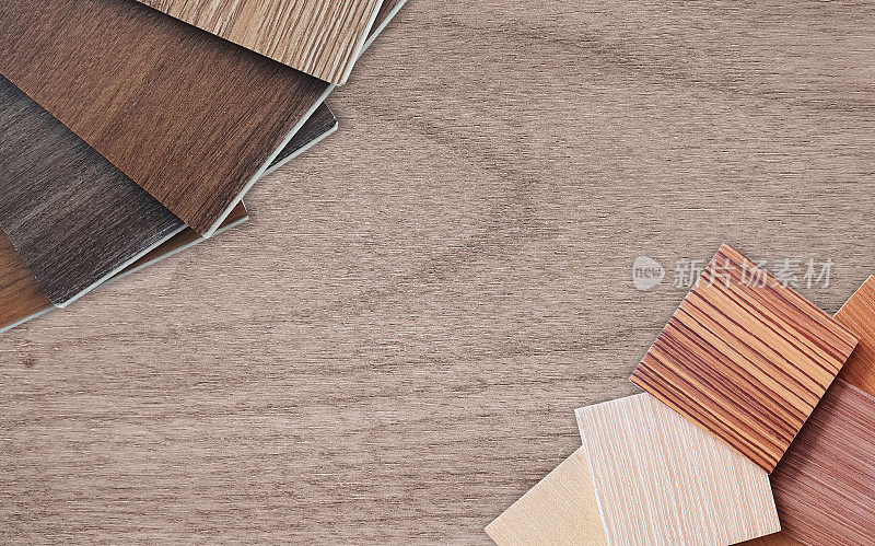 许多薄的木质样品，包括木质乙烯基地板瓷砖，木制贴面层压在室内设计的橡木木桌上。多种类型的木材样品，包括橡木，核桃，山核桃，白蜡树。