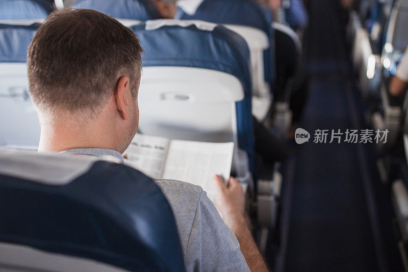 中年男子在飞机上看杂志