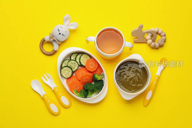 健康的婴儿食品在碗和配件在黄色背景，平铺