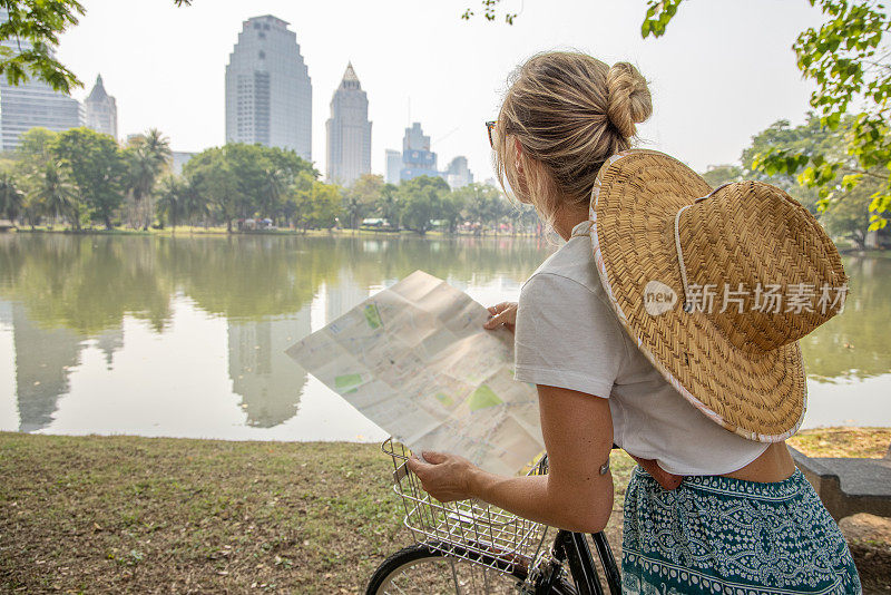 一名年轻女子骑着自行车探索亚洲，她看着地图