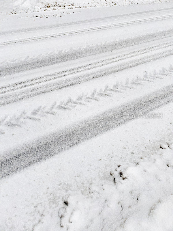 汽车和拖拉机的轮胎印在路上刚落下的雪上。