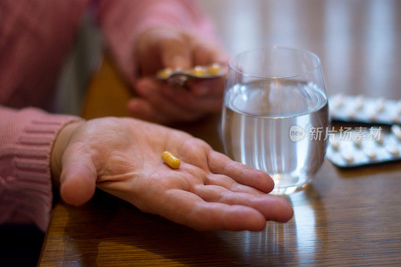 老年妇女手里拿着药丸的特写