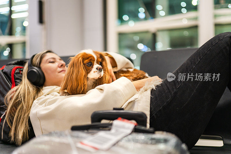 一名女子带着她的狗在机场等待她的航班