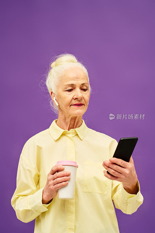 老妇人拿着一杯咖啡在网上看电影或视频