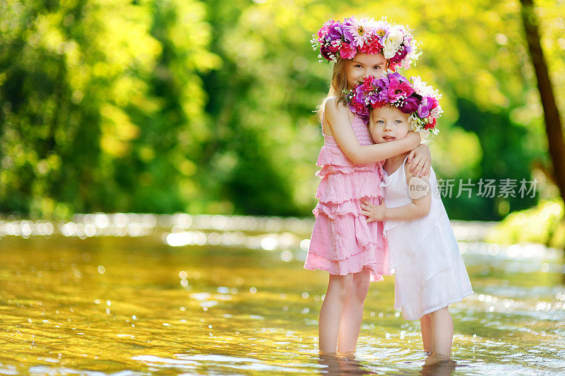 夏日，两个可爱的小姐妹头戴花冠，站在河边