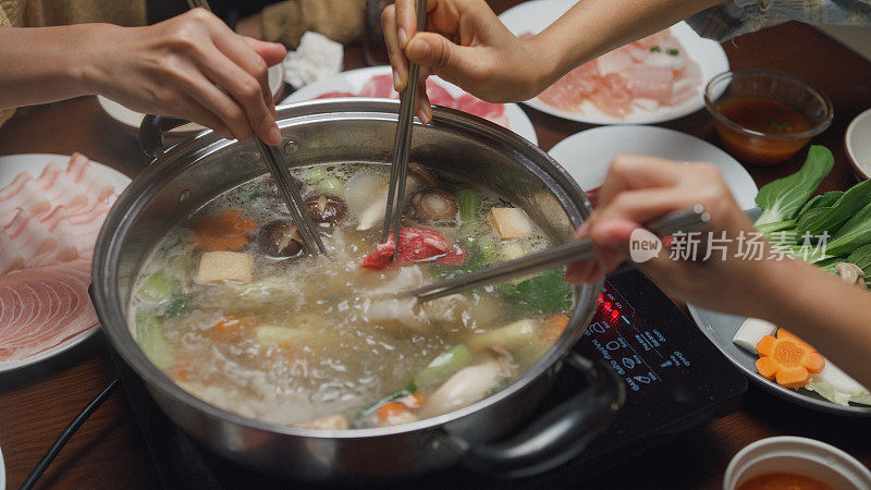 特写:一群快乐的亚洲朋友晚上在家里吃春节团圆饭时吃着火锅。生活方式享受美食。