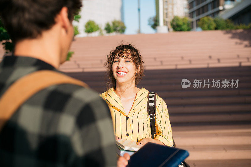 年轻的女学生和朋友站在外面讨论学习