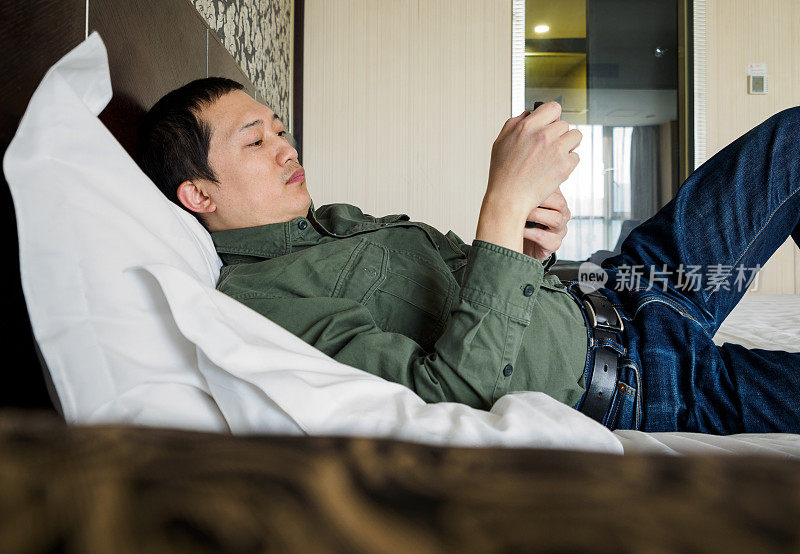 躺在酒店床上玩手机的男人