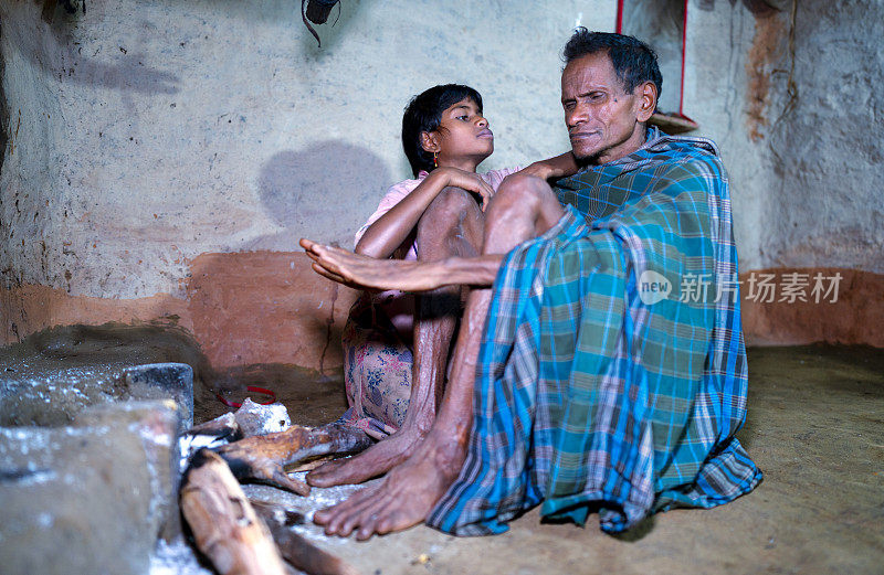 来自印度奥里萨邦邦达部落的父女在壁炉前。来自印度奥里萨邦邦达部落的父女在壁炉前。那女孩靠在她父亲的膝盖上，用一种茫然的眼神看着他