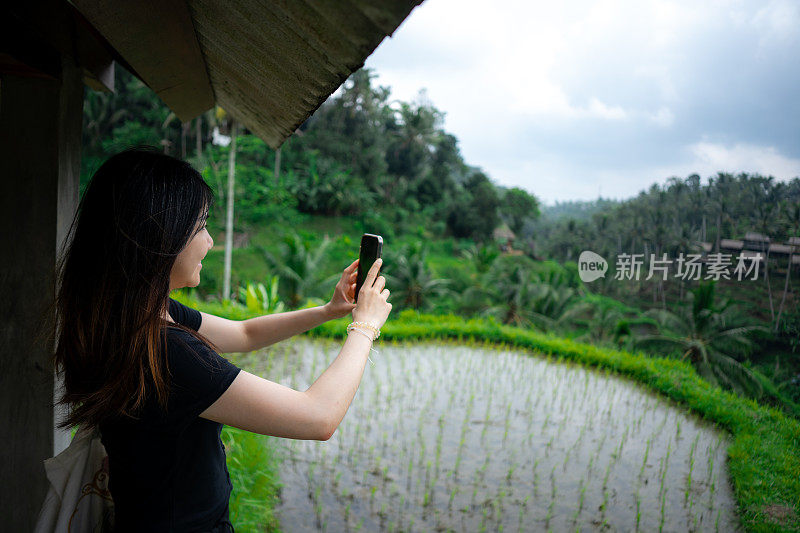 独自女旅行者在巴厘岛的稻田风景中漫步并拍照