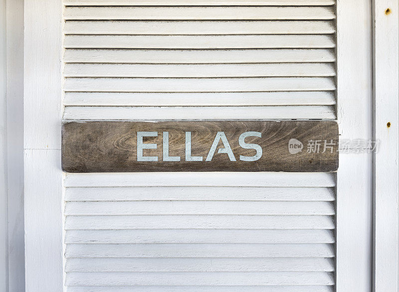 一扇白色的门上挂着一个牌子，上面写着西班牙语“ellas”