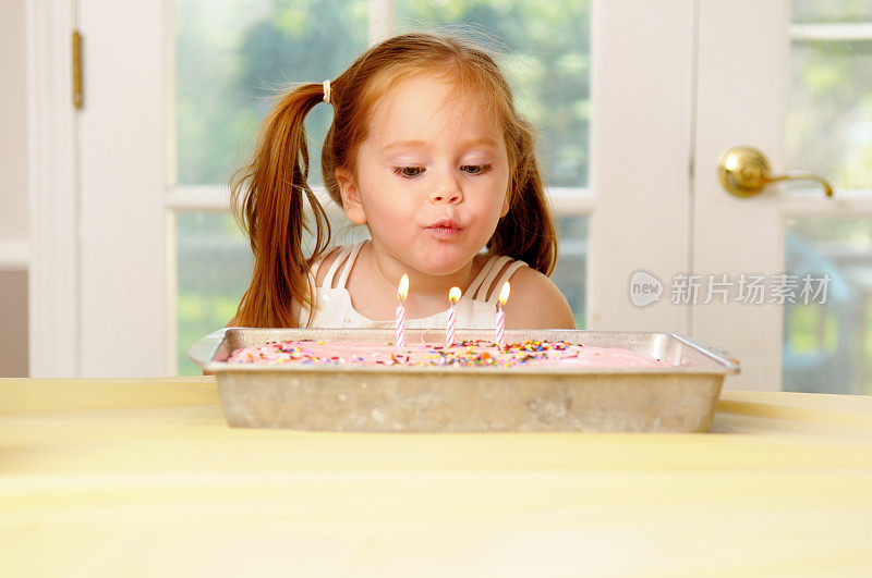 小女孩吹灭生日蛋糕上的蜡烛