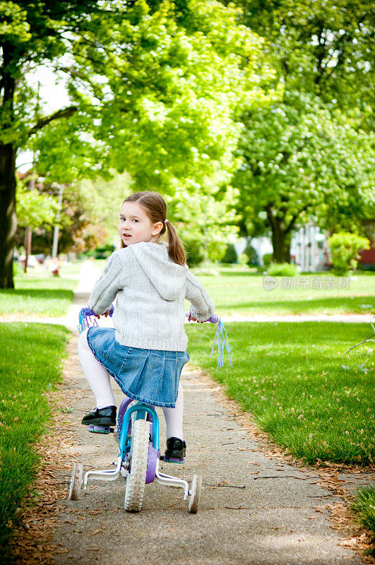 小女孩在人行道上骑自行车