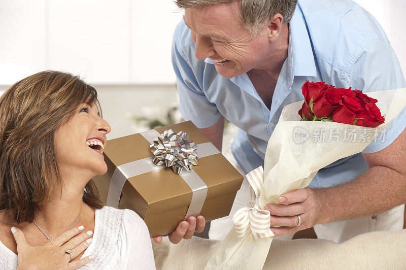 一个男人给他幸福的妻子一份礼物和玫瑰