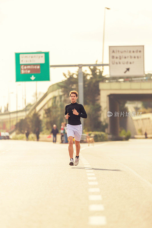 年轻的男运动员在马路上跑步