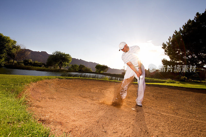 男高尔夫球手使沙坑击球与沙楔