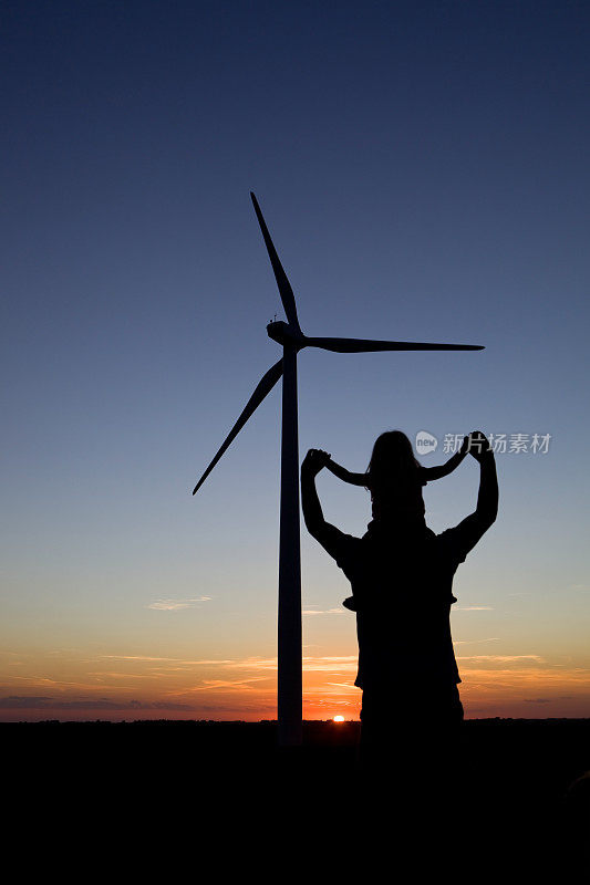 日落时分的风力涡轮机旁，父亲肩上的小女孩