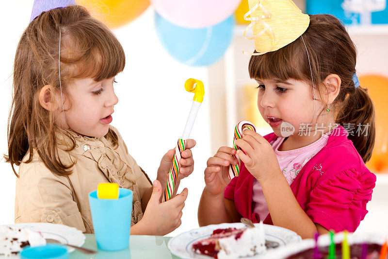 两个小女孩在生日派对上拿着棒棒糖