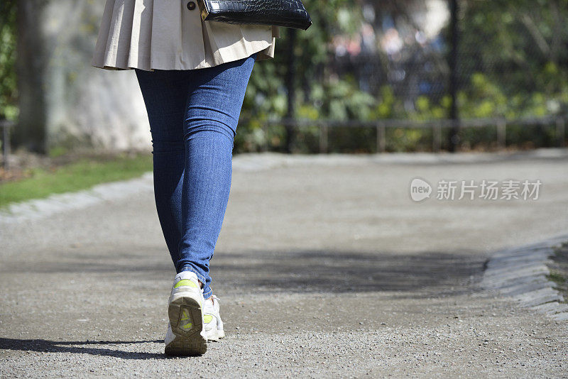 年轻女子拿着漂亮的手提包在公园里散步