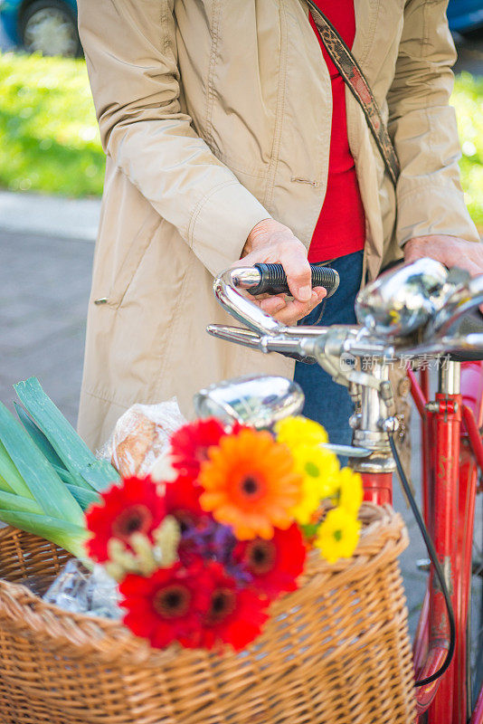 女人拿着自行车和装满鲜花的篮子