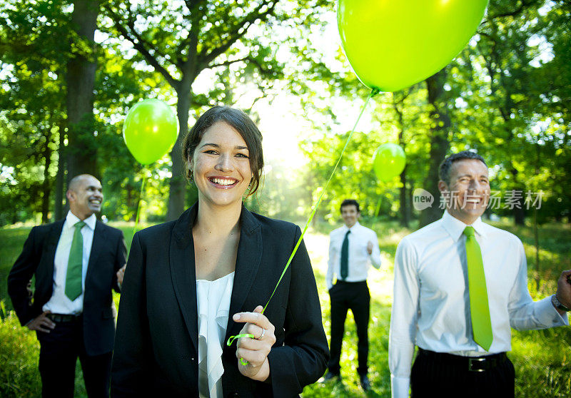 绿色商业团队举着气球站在户外