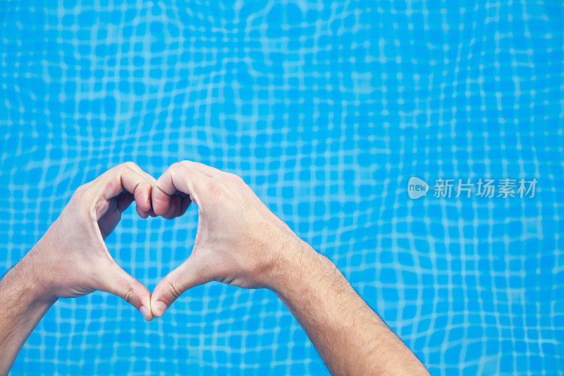 双手呈心形放在游泳池上方。