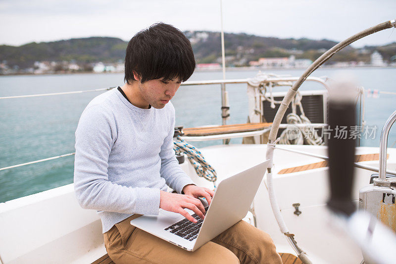 一个人坐在游艇上用电脑