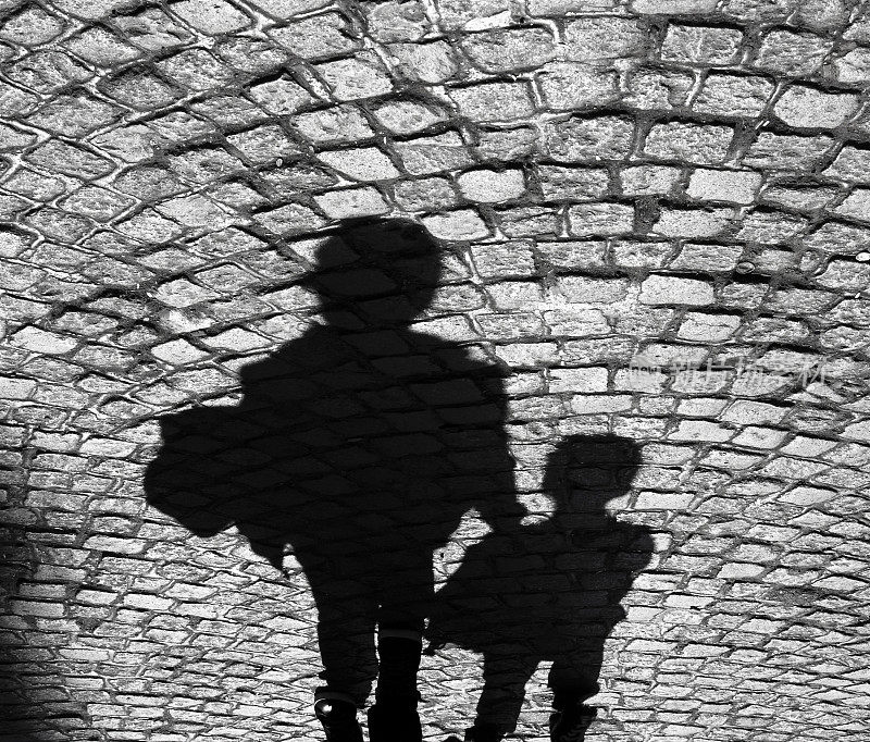 一个大人和一个小孩在鹅卵石人行道上的影子