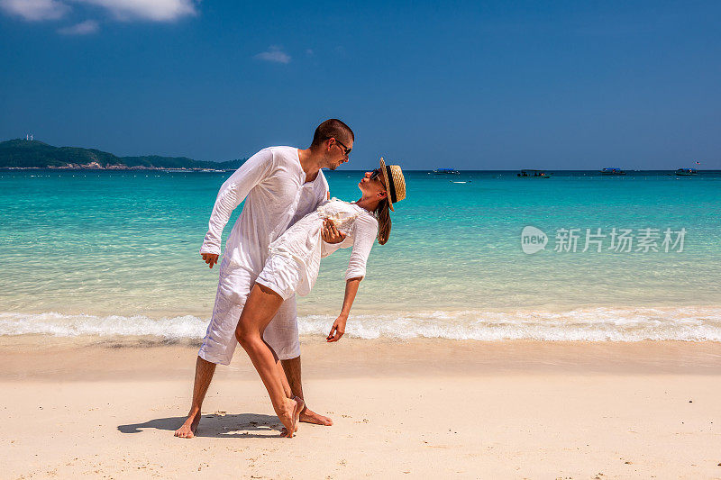 一对穿着白色衣服的情侣在沙滩上玩