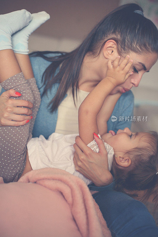 年轻的母亲在家里抱着女儿，抱着女孩。