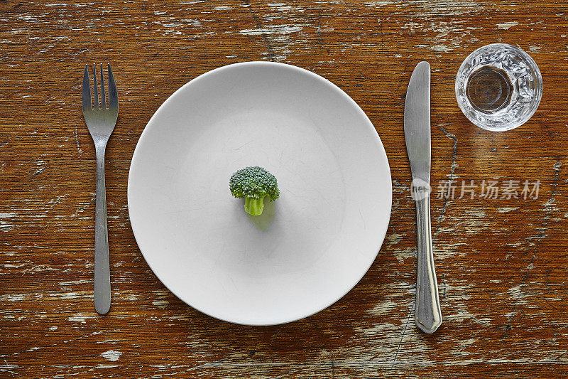 用刀叉把单一的花椰菜放在盘子里，比喻节食