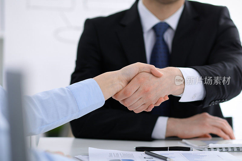 不知名的商务人士握手结束会议的特写。握手、协议或成功概念在人们的交际中