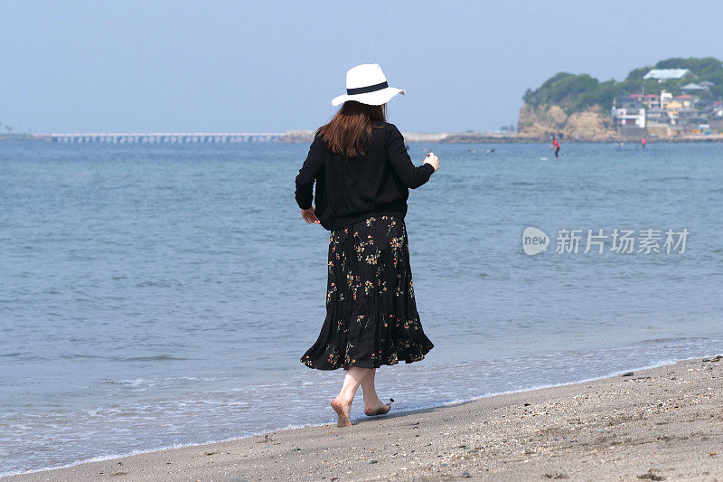 年轻女子走在潮湿的沙滩上