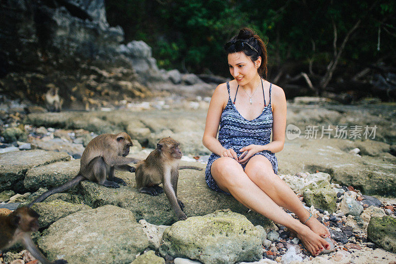 一名年轻女子在泰国皮皮岛的猴子海滩上与猴子玩耍