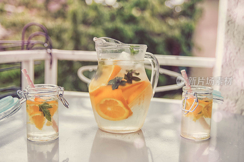 橙汁和柠檬汁在水罐和玻璃杯孤立的白色