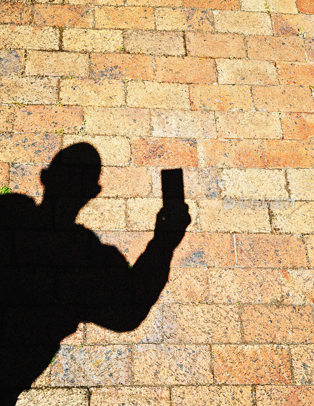 一个男人在砖墙边自拍的影子剪影