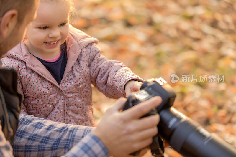 爸爸用专业相机给他可爱的小女儿看照片。