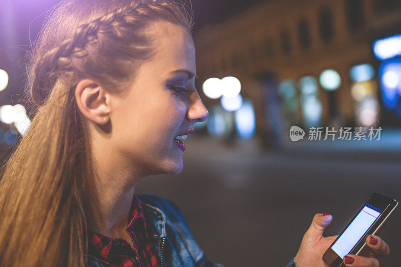 晚上在城市街道上打电话的女人