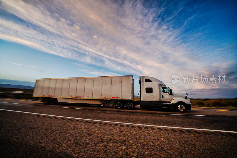 在一个戏剧性的天空下的黄昏高速公路上的长途半挂车