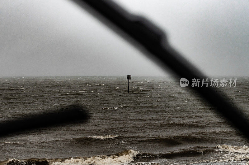 透过汽车挡风玻璃看到暴风雨的大海和低潮标志